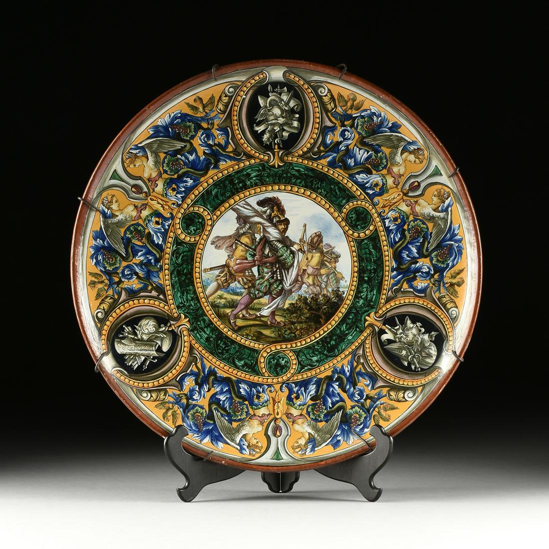 A LARGE ITALIAN RENAISSANCE STYLE MAJOLICA HISTORIATO: A LARGE ITALIAN RENAISSANCE STYLE MAJOLICA HISTORIATO CHARGER, SIGNED, LATE 19TH/EARLY 20TH CENTURY, of circular form and a brick red painted rim on a broad border of paired harpies issuing from scrol