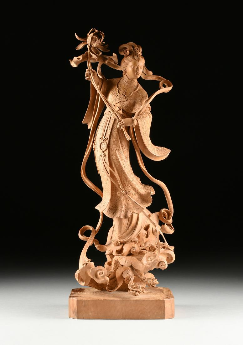 A LARGE CHINESE/TAIWANESE WOOD SCULPTURE OF LAN CAIHE,: A LARGE CHINESE/TAIWANESE WOOD SCULPTURE OF LAN CAIHE, CIRCA 1982, beautifully carved from a single block of wood and representing the maiden deity with an elaborate chignon hairstyle and a serene smi