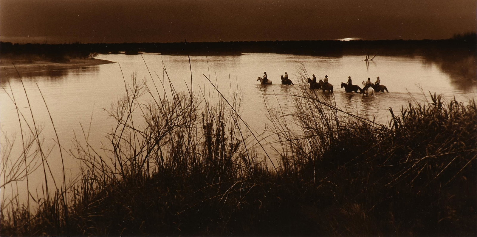 BILL WHITLIFF (American/Texas 1940-2019) A PHOTOGRAPH,: BILL WHITLIFF (American/Texas 1940-2019) A PHOTOGRAPH, "Cattle Crossing the Rio Grande, From Lonesome Dove Miniseries," sepia toned gelatin silver print on paper, signed L/R in margin. 12" x 23"