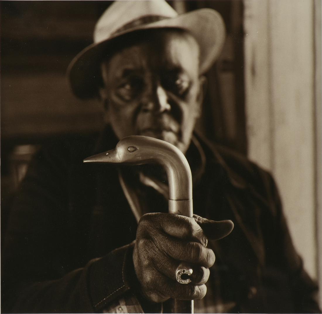JACK SPENCER (American b. 1951) A PHOTOGRAPH, "Portrait: JACK SPENCER (American b. 1951) A PHOTOGRAPH, "Portrait of a Man with Cane," black and white photo on paper, signed L/R, "Spencer," in margin. 9 1/2" x 9 1/2"