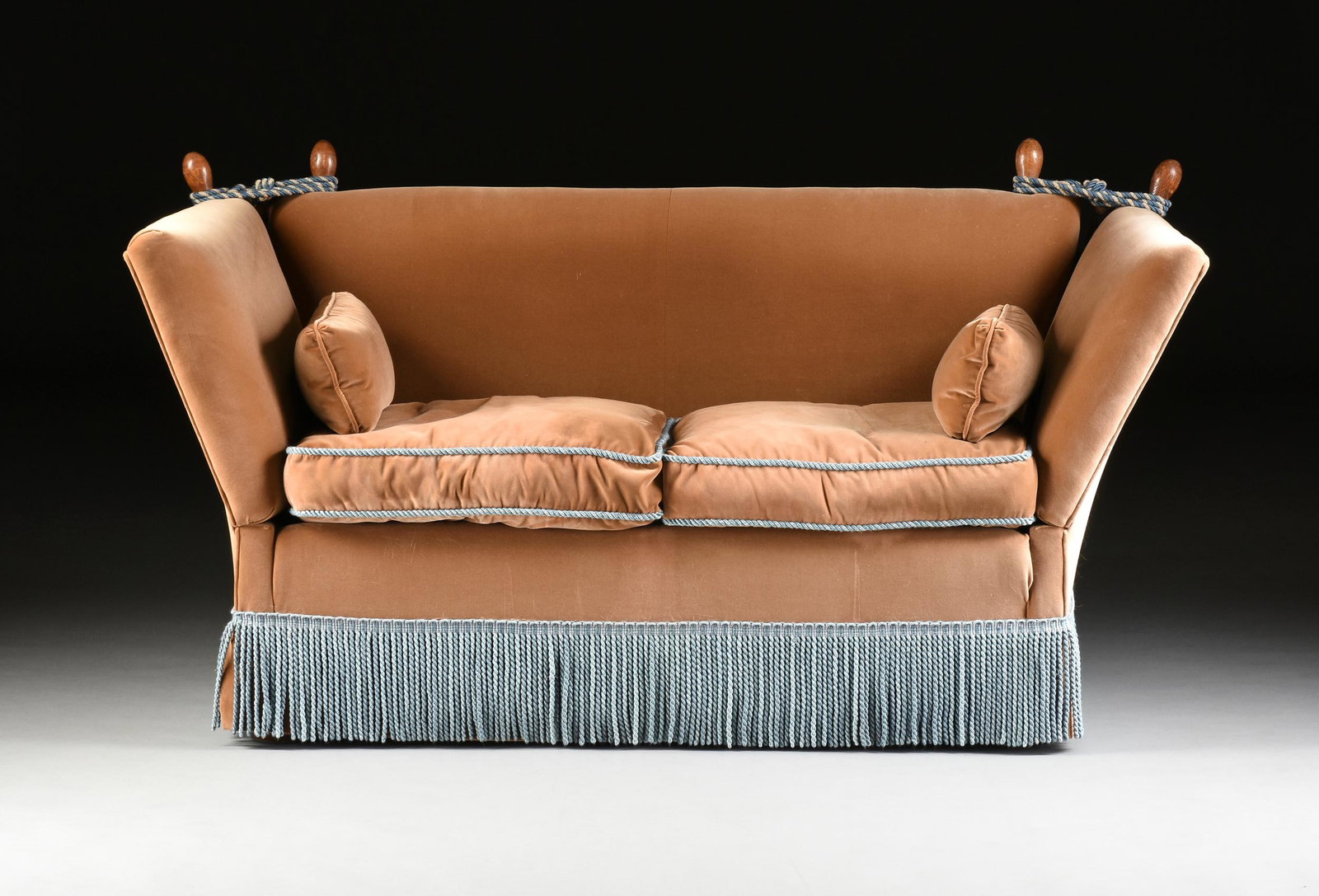 A KNOLE STYLE VELVET UPHOLSTERED LOVE SEAT, MODERN,: A KNOLE STYLE VELVET UPHOLSTERED LOVE SEAT, MODERN, the rectangular back with corner stained oak ovoid finials, flanked by ovoid finial topped adjustable sides bound with blue and white silk twist cor