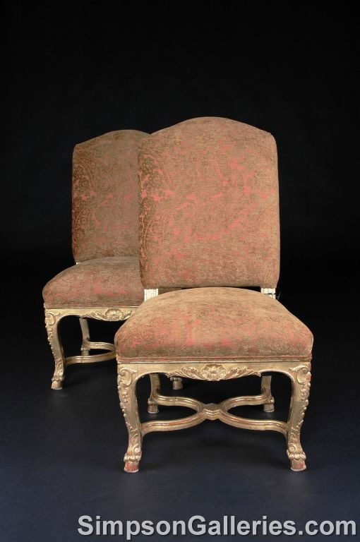 A PAIR OF RÉGENCE GILTWOOD CHAISES, each with arc: A PAIR OF RÉGENCE GILTWOOD CHAISES, each with arched padded backrest on fluted supports above a trapezoidal seat with a serpentine seat rail centering a carved shell issuing stylized leaves flanked b