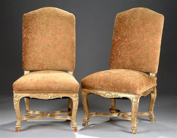 A PAIR OF RÉGENCE GILTWOOD CHAISES, each with arch: A PAIR OF RÉGENCE GILTWOOD CHAISES, each with arched padded backrest on fluted supports above a trapezoidal seat with a serpentine seat rail centering a carved shell issuing stylized leaves flanked b