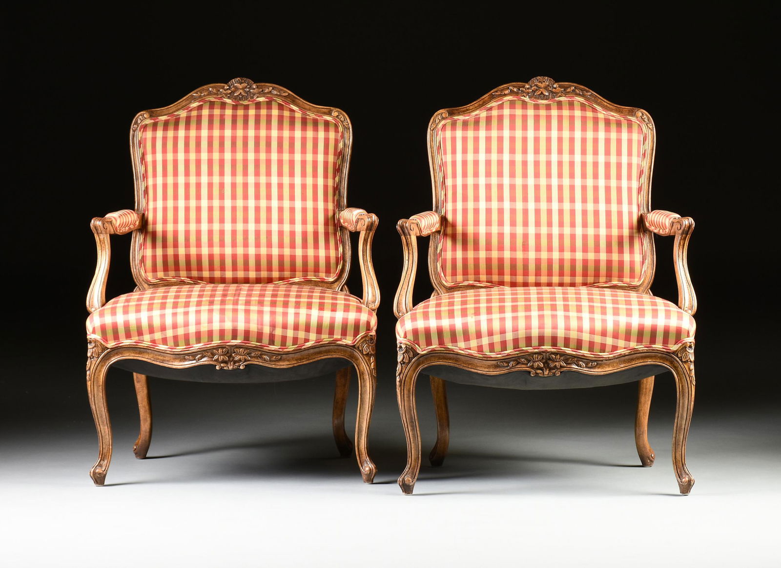 A PAIR OF LOUIS XV STYLE PLAID SILK UPHOLSTERED AND: A PAIR OF LOUIS XV STYLE PLAID SILK UPHOLSTERED AND CARVED WOOD FAUTEUILS À LA REINE, MODERN, each with a serpentine arched crest rail centering trailing leafy vine details, on a molded undulating sq