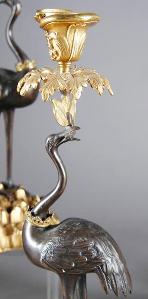 A PAIR OF CONTINENTAL GILT AND PATINATED BRONZE BIR: A PAIR OF CONTINENTAL GILT AND PATINATED BRONZE BIRD FORM CANDLESTANDS, stamped Abbott, each modeled as a long legged marsh bird with a crown collar holding palm fans, beneath an acanthus cast drip pa