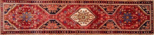 A TABRIZ RUNNER, the claret field patterned with di: A TABRIZ RUNNER, the claret field patterned with diamond lozenges and stylized flower heads, the primary border with floral rosettes. 2.5 x 11.2