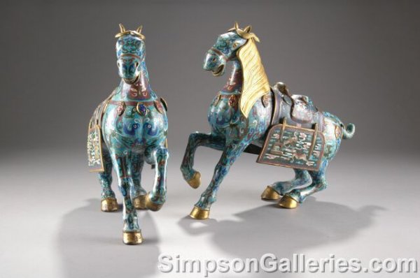 A PAIR OF CHINESE CLOISONNÉ HORSES, each with gilt: A PAIR OF CHINESE CLOISONNÉ HORSES, each with gilt bronze manes and removable saddles, on a blue ground, and decorated with precious objects, foliate scrolls, and sacred bats. Height: 17", length: 18