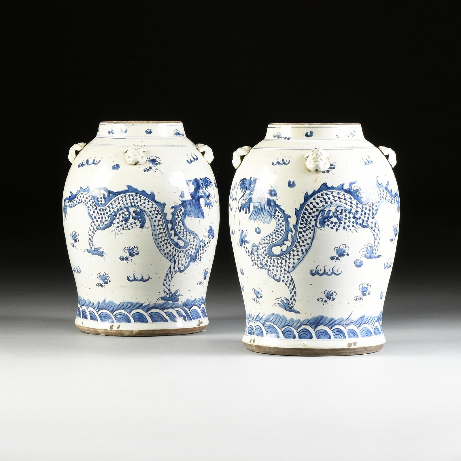 A PAIR OF JAPANESE EXPORT BLUE AND WHITE EARTHENWARE: A PAIR OF JAPANESE EXPORT BLUE AND WHITE EARTHENWARE DRAGON JARS, MID/LATE 19TH CENTURY, with a ballooning body decorated with applied relief beast masks painted with an undulating dragon with lattice