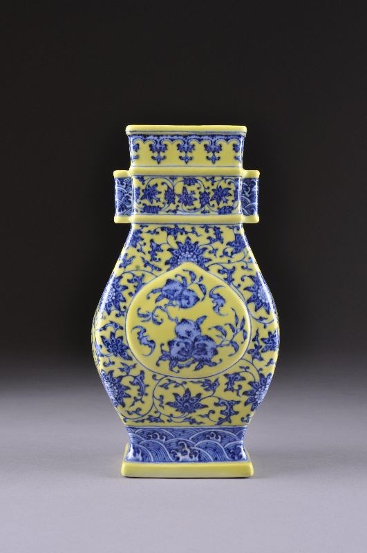 A VINTAGE CHINESE YELLOW GROUND, BLUE, AND WHITE V: A VINTAGE CHINESE YELLOW GROUND, BLUE, AND WHITE VASE, FANGHU, 20TH CENTURY, of flattened pear shape and centering raised molded reserves enclosing fruiting peach branches and bats on a ground of scro