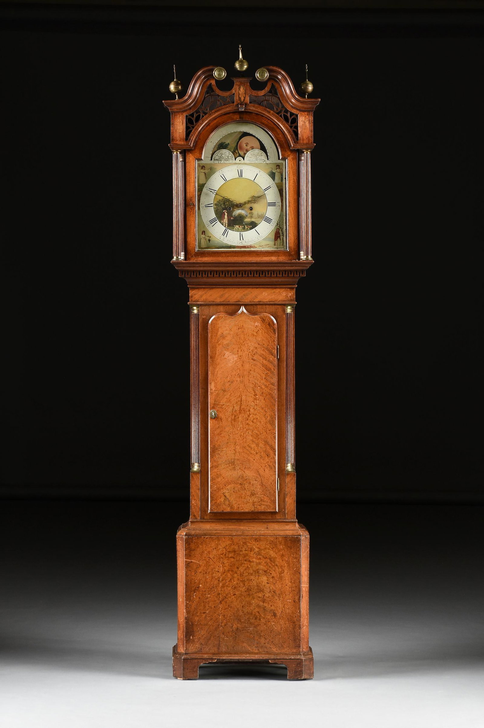A GEORGE III INLAID FLAME MAHOGANY TALL CASE CLOCK,: A GEORGE III INLAID FLAME MAHOGANY TALL CASE CLOCK, SIGNED BRIGG KIGHLEY, HMS 1795 RODNEY, LATE 18TH CENTURY, the arched rectangular hand painted dial with conforming lunar phases and paired northern 