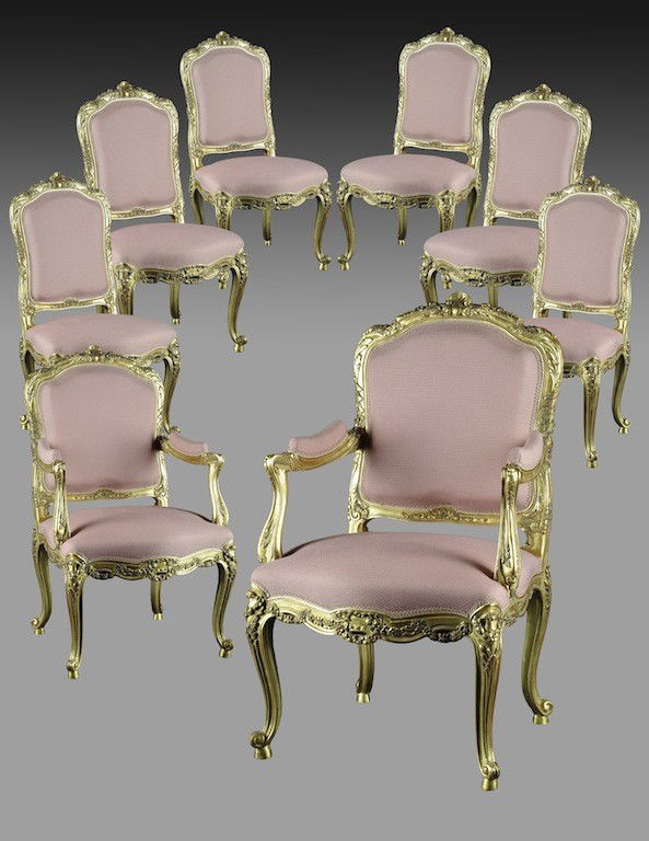 A LOUIS XV PARCEL GILT AND CARVED WOOD SUITE, 20TH: A LOUIS XV PARCEL GILT AND CARVED WOOD SUITE, 20TH CENTURY, comprising two fauteuils and six chaises, each having an arched crest rail centering a stylized scrolling shell issuing trailing flowers abo