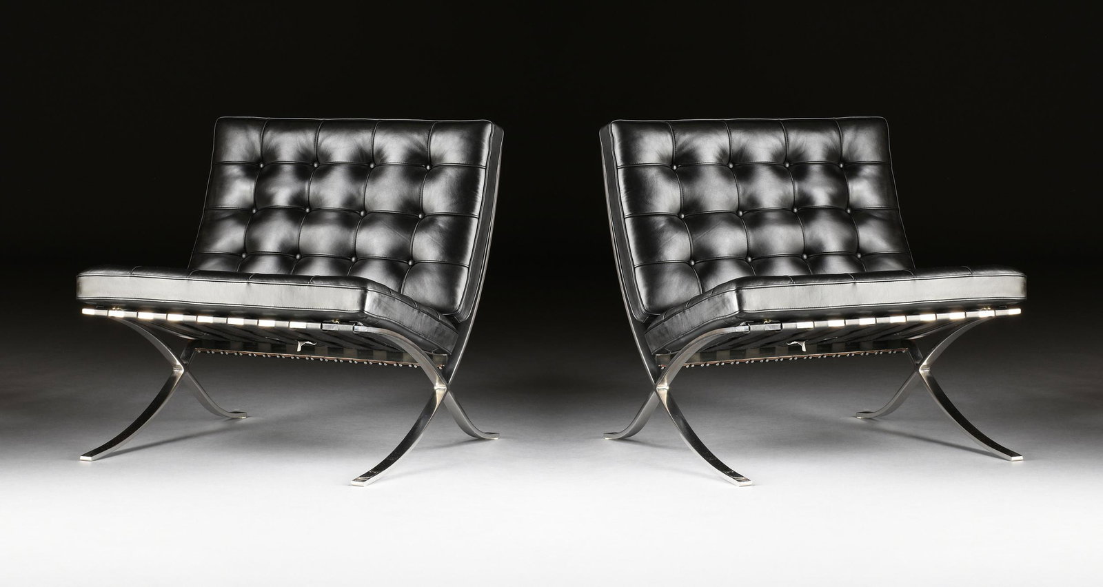 A PAIR OF BARCELONA CHAIRS IN BLACK LEATHER AND POLISHED STAINLESS STEEL, DESIGNER MIES VAN DER: A PAIR OF BARCELONA CHAIRS IN BLACK LEATHER AND POLISHED STAINLESS STEEL, DESIGNER MIES VAN DER ROHE, BY KNOLL GROUP, 1990s, each with a rectangular button tufted black leather back and seat cushion, 