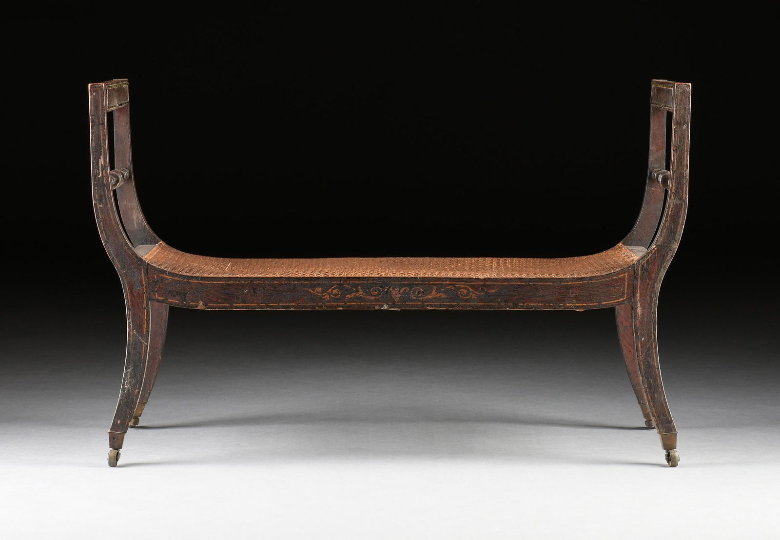 A FEDERAL FAUX BOIS PAINTED AND CANED WOOD WINDOW SEAT, CIRCA 1830,: A FEDERAL FAUX BOIS PAINTED AND CANED WOOD WINDOW SEAT, CIRCA 1830, hand painted throughout in a faux rosewood centering scrolling foliate decoration on recessed panel crest rails above turned splats