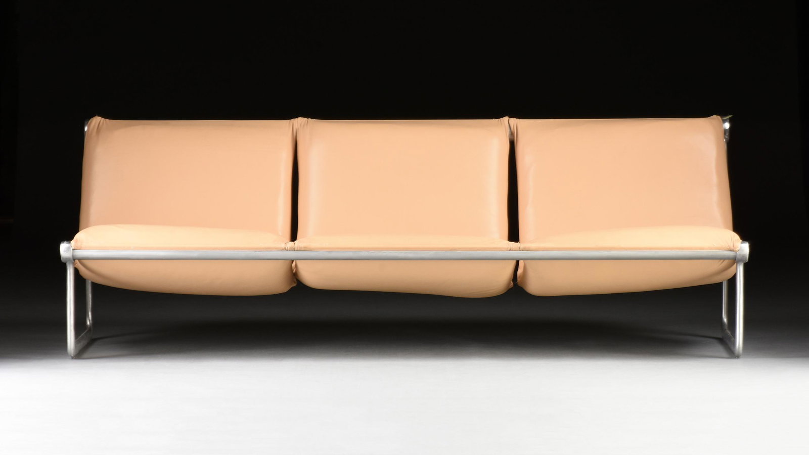 A MID CENTURY MODERN FIVE PIECE LEATHER UPHOLSTERED AND BRUSHED ALUMINUM BEAM SEATING GROUP,: A MID CENTURY MODERN FIVE PIECE LEATHER UPHOLSTERED AND BRUSHED ALUMINUM BEAM SEATING GROUP, 1960s/'70s, each padded and upholstered in a later tan leather within shaped rectangular elliptical brushed