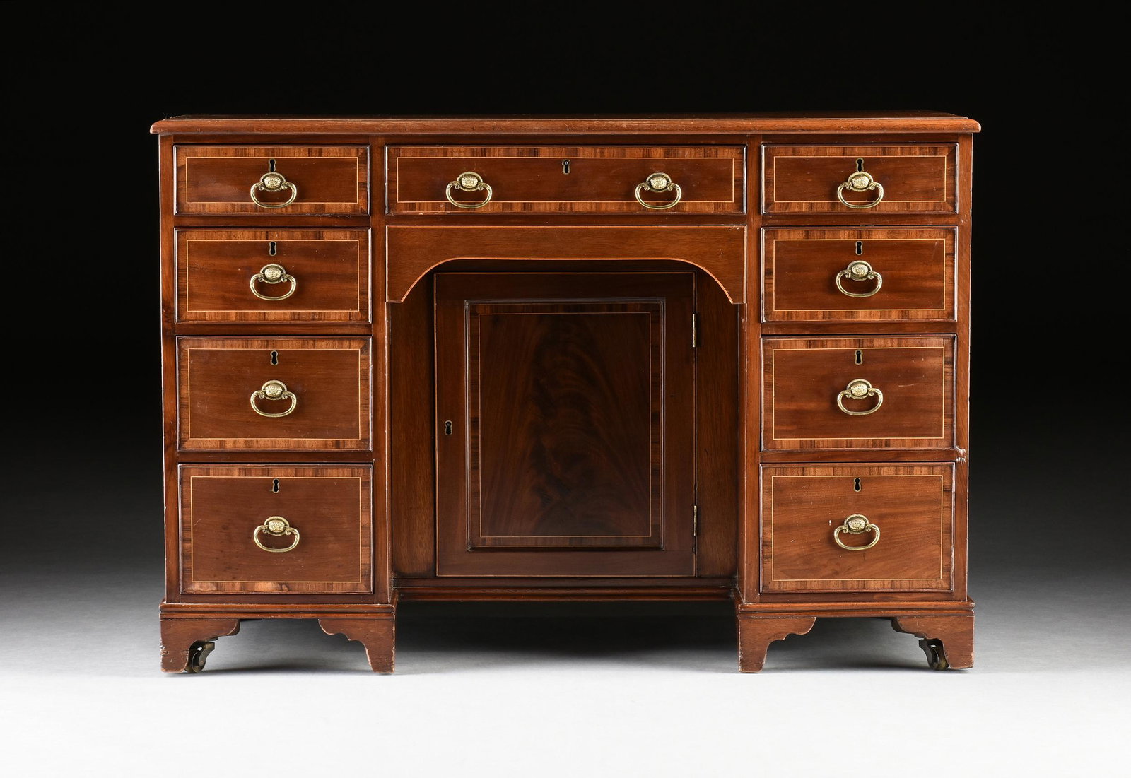 A GEORGE III MAHOGANY KNEEHOLE DESK,: A GEORGE III MAHOGANY KNEEHOLE DESK, the rectangular top mahogany panel with string inlay and crossbanding, above a central long drawer over a shallow kneehole drawer above a recessed cabinet opening 