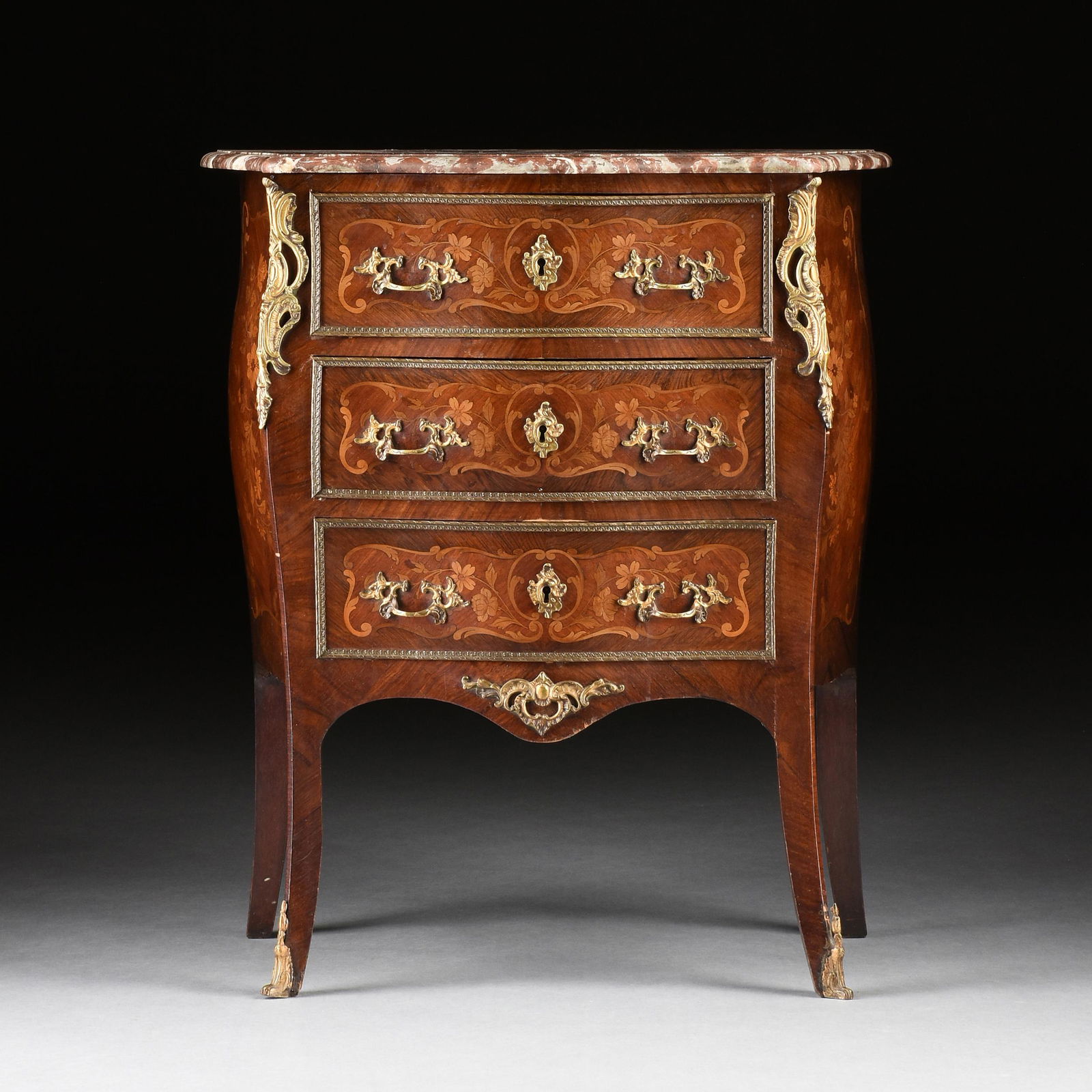 A LOUIS XV STYLE MARBLE TOPPED AND ORMOLU MOUNTED FLORAL MARQUETRY INLAID PETITE COMMODE, FRENCH,: A LOUIS XV STYLE MARBLE TOPPED AND ORMOLU MOUNTED FLORAL MARQUETRY INLAID PETITE COMMODE, FRENCH, LATE 19TH CENTURY, the serpentine rectangular Rouge de France marble top with bull nose carved edge, a
