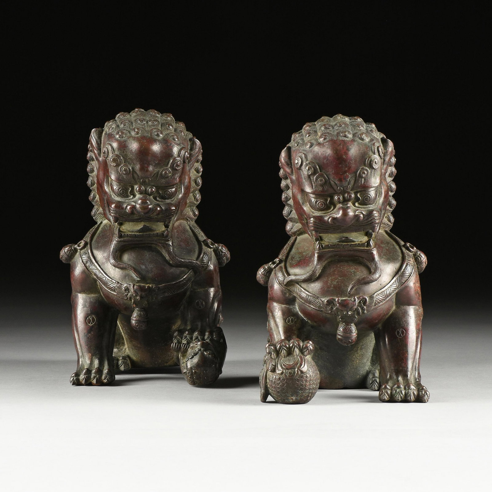 A PAIR OF MING DYNASTY STYLE LACQUERED BRONZE FU DOG GUARDIAN LIONS, QING DYNASTY (1644-1912),: A PAIR OF MING DYNASTY STYLE LACQUERED BRONZE FU DOG GUARDIAN LIONS, QING DYNASTY (1644-1912), after the Forbidden Palace shi guardians, parcel gilt and dark red lacquered cast bronze figures of 