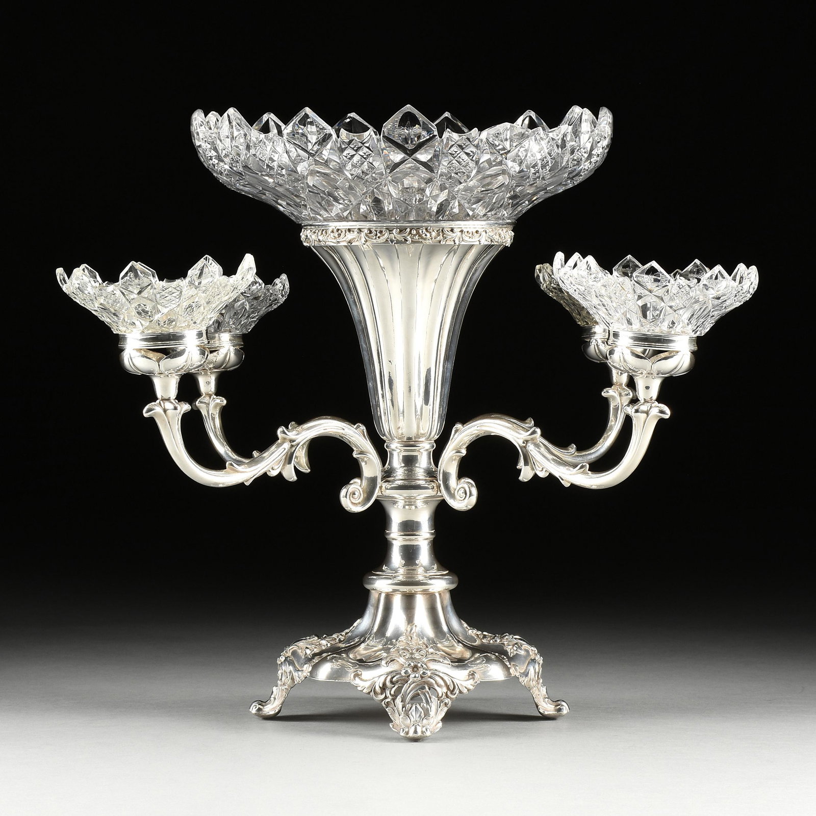A VICTORIAN SHEFFIELD STYLE SILVER PLATE AND CUT CRYSTAL FOUR LIGHT EPERGNE, PROBABLY ENGLISH, CIRCA: A VICTORIAN SHEFFIELD STYLE SILVER PLATE AND CUT CRYSTAL FOUR LIGHT EPERGNE, PROBABLY ENGLISH, CIRCA 1900, the central bowl with petal form rests upon a central fluted tulip vase with relief collar ov