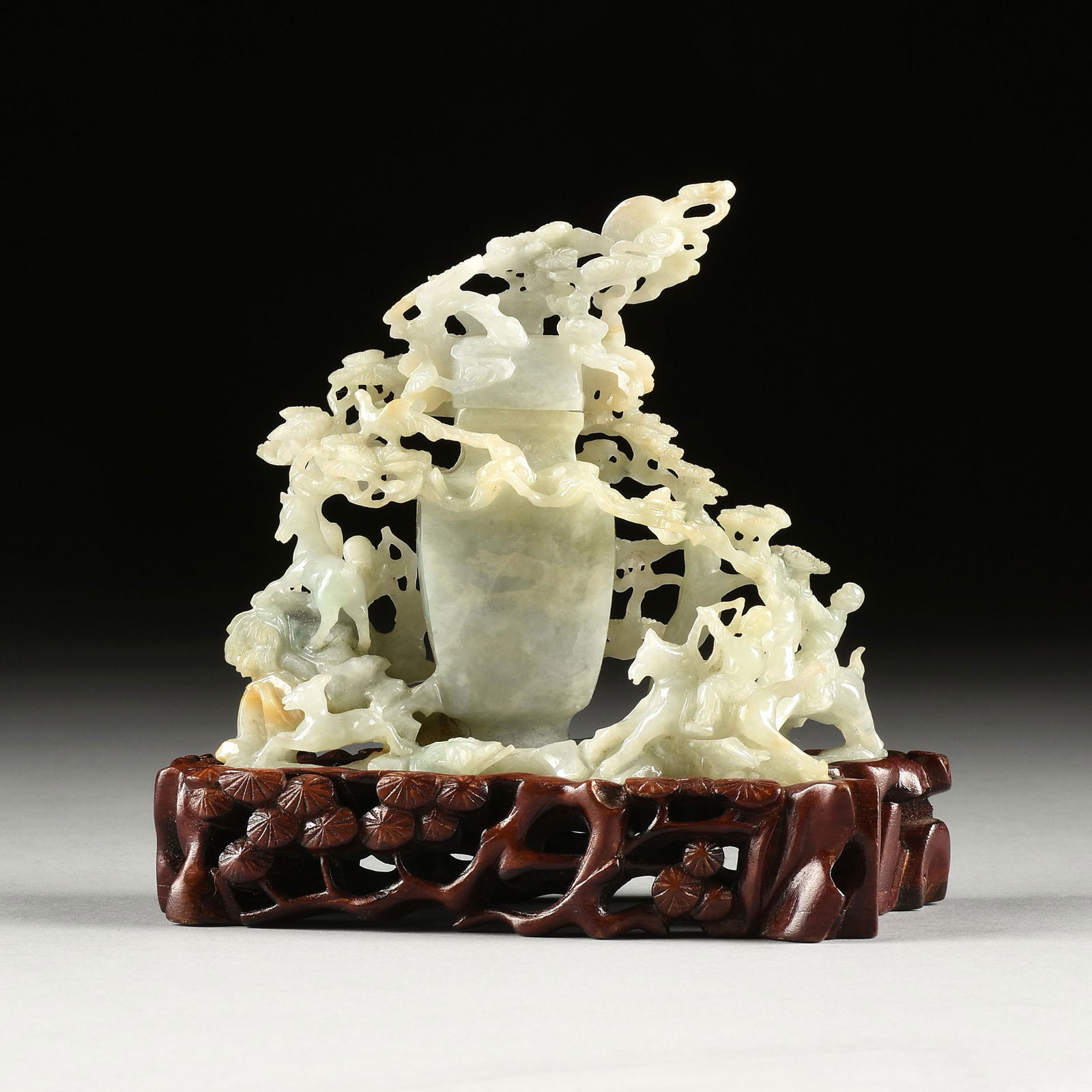 A CHINESE CELADON JADE COVERED VASE ON STAND, MOONLIT HUNTERS WITH FAWN, DOG, AND PHOENIX GROUP,: A CHINESE CELADON JADE COVERED VASE ON STAND, MOONLIT HUNTERS WITH FAWN, DOG, AND PHOENIX GROUP, POSSIBLY QING DYNASTY (1644-1912), the pale translucent green jade with mutton fat and russet inclusion