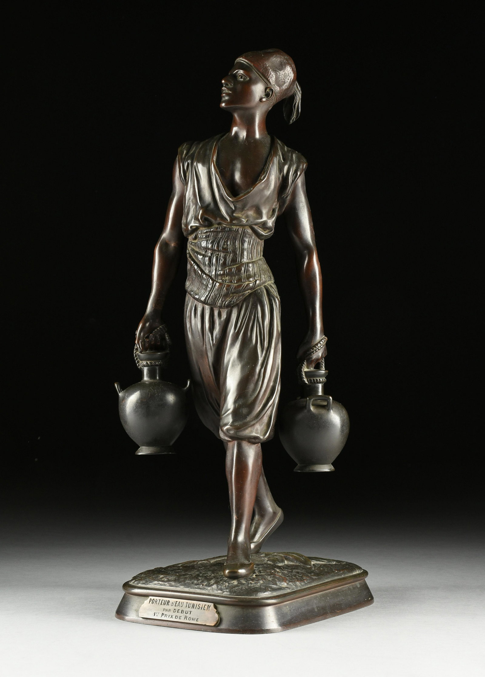 after JEAN DIDIER DEBUT (French 1824-1893) A SCULPTURE, "Porteur d'Eau Tunisien," 19TH/20TH CENTURY,: after JEAN DIDIER DEBUT (French 1824-1893) A SCULPTURE, "Porteur d'Eau Tunisien," 19TH/20TH CENTURY, bronze with dark brown patina, inscribed, "Debut," on the ground at base, with the foundry mark, "B