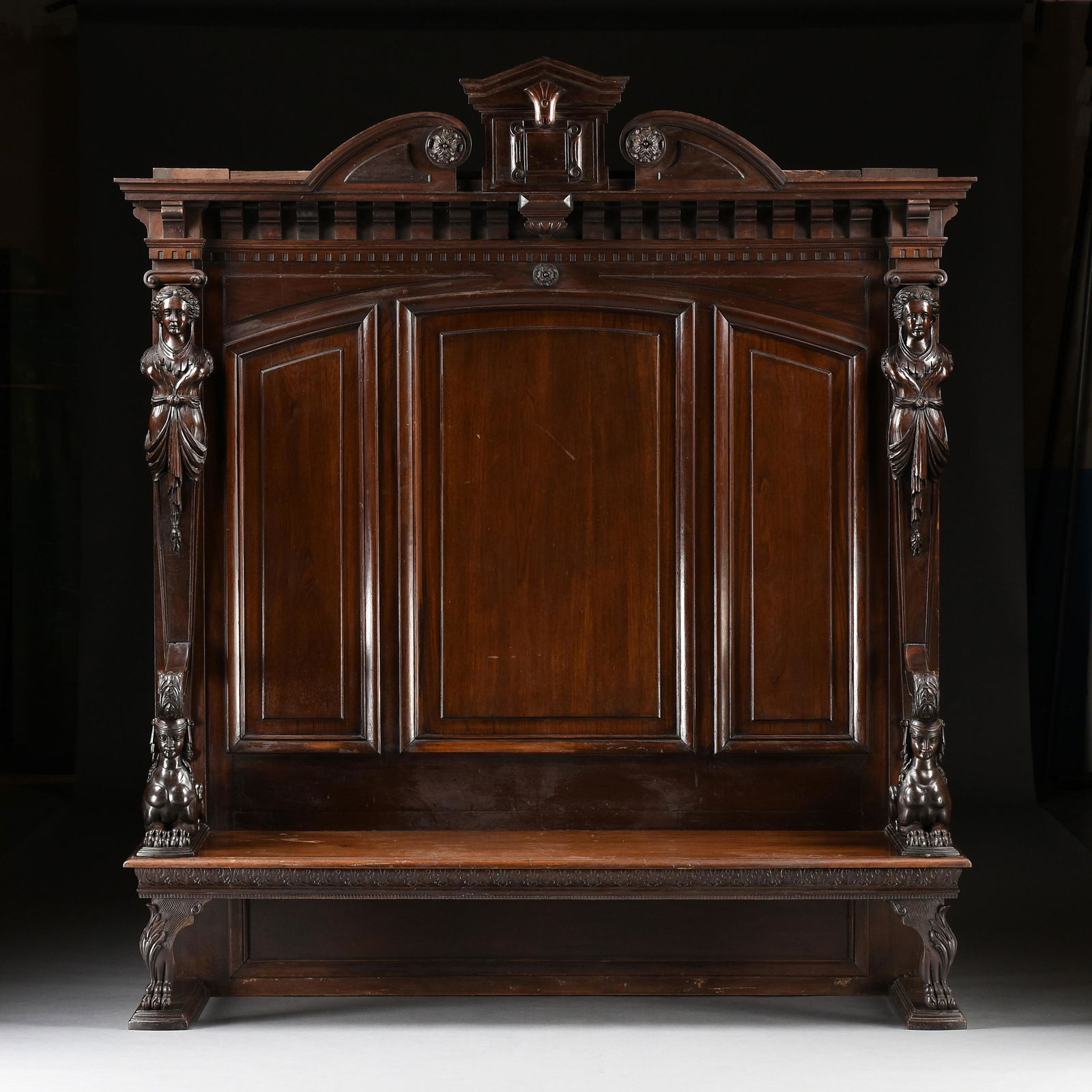 A NEOCLASSICAL WALNUT AND MAHOGANY HALL BENCH SETTLE, PROBABLY ENGLISH, LATE 19TH CENTURY,: A NEOCLASSICAL WALNUT AND MAHOGANY HALL BENCH SETTLE, PROBABLY ENGLISH, LATE 19TH CENTURY, likely inspired by the designs of Robert Adams (1728-1792), the pointed pediment centers a square lozenge ato