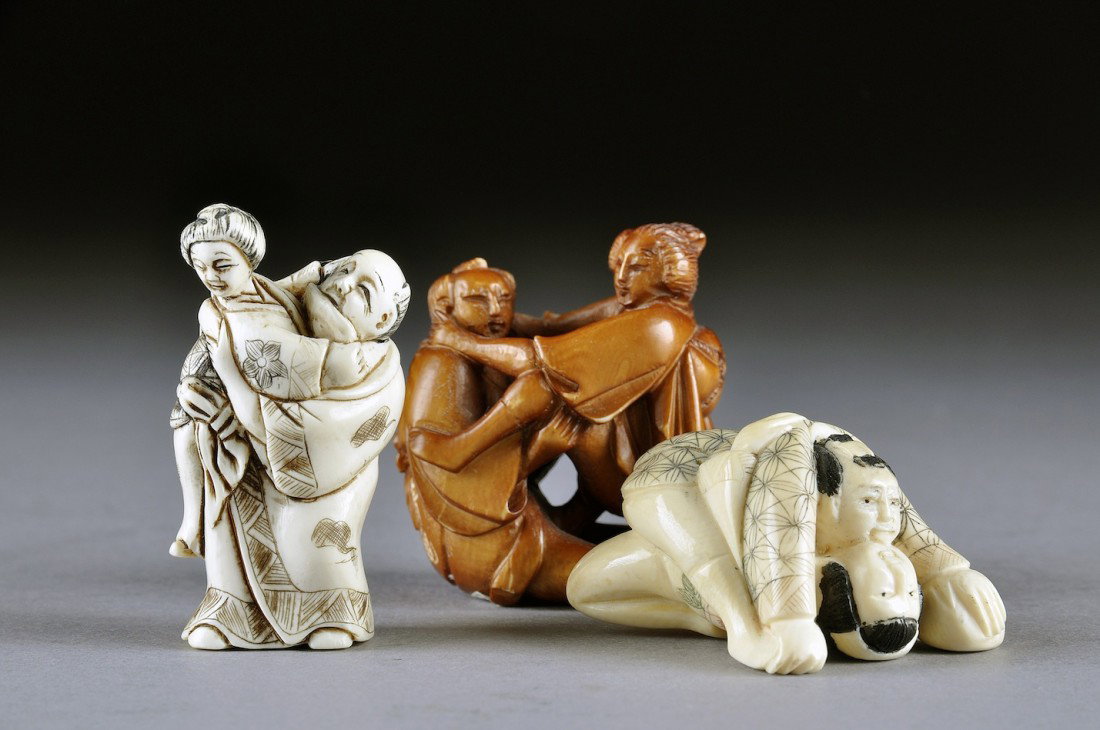 THREE VINTAGE JAPANESE CARVED IVORY EROTIC NETSUKES: THREE VINTAGE JAPANESE CARVED IVORY EROTIC NETSUKES, 20th CENTURY, one tea-brown stained group of a clothed couple in an intimate embrace with incised two character mark signature, height: 1 7/8"; an 