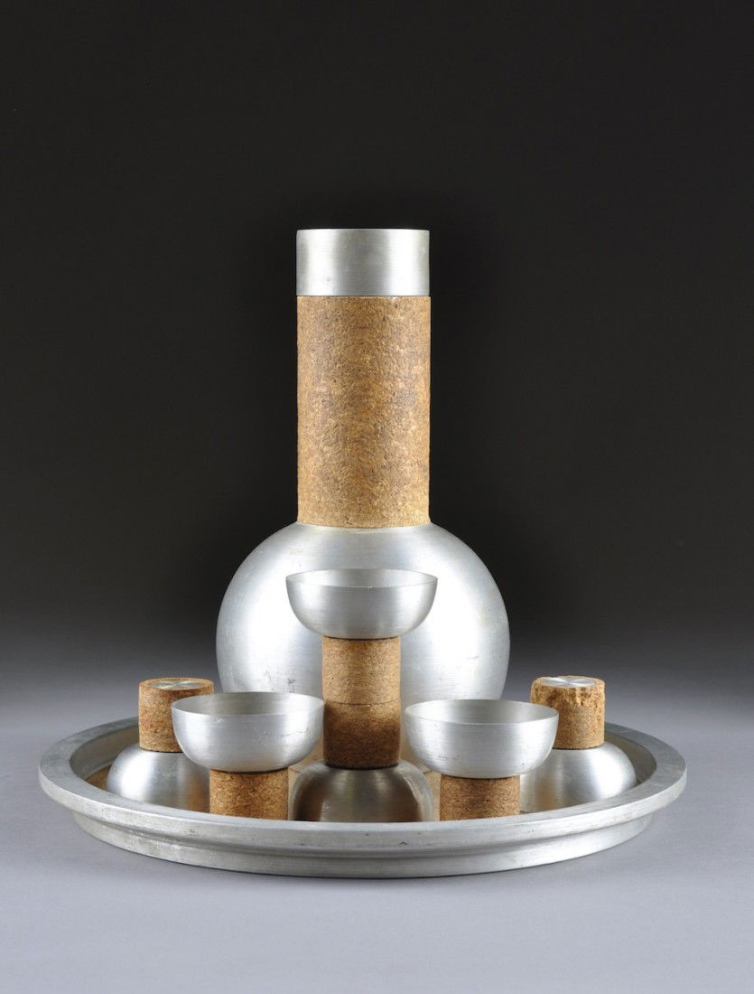 A RARE RUSSEL WRIGHT COCKTAIL SET, MODEL 326, CIRC: A RARE RUSSEL WRIGHT COCKTAIL SET, MODEL 326, CIRCA 1930, of spun aluminum and cork comprising a decanter with strainer and lid, six cups and a tray, each signed with impressed manufacturer's mark. He