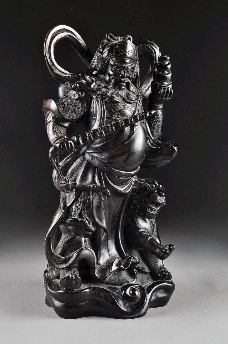 A CHINESE CARVED ZITAN FIGURE OF A GUARDIAN KING W: A CHINESE CARVED ZITAN FIGURE OF A GUARDIAN KING WARRIOR the powerful corpulent figure having nicely detailed armor partially concealed by draping robes and holding a sheathed sword in his right hand