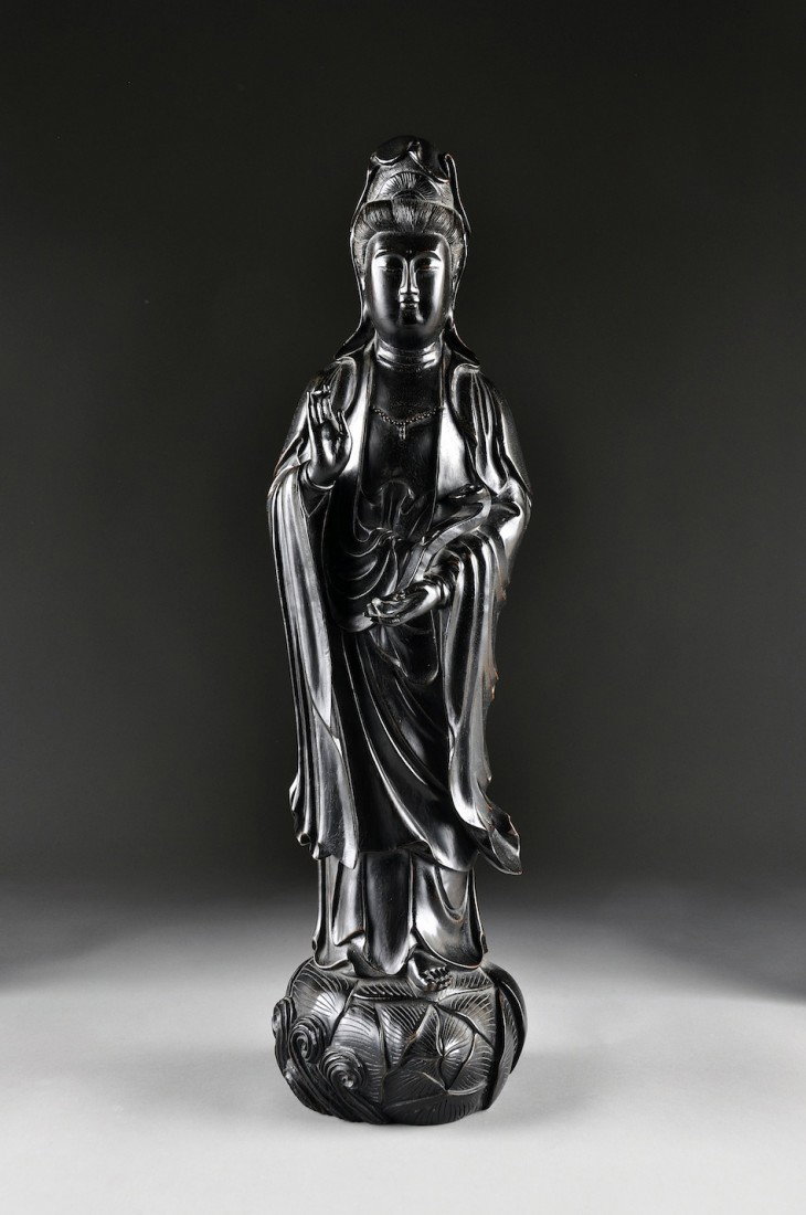 A CHINESE CARVED ZITAN FIGURE OF GUANYIN, 20TH CEN: A CHINESE CARVED ZITAN FIGURE OF GUANYIN, 20TH CENTURY, modeled in a standing position, wearing long draping robes, with a serene expression, and holding a ruyi scepter, raised on a stylized lotus blo