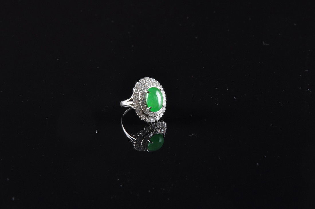 AN 18K CHINESE JADEITE JADE AND DIAMOND LADY'S RIN: AN 18K CHINESE JADEITE JADE AND DIAMOND LADY'S RING, the white gold mounting set with natural, type “A” jadeite jade oval measuring 9.2 x 12.0 millimeters, exceptional green color, translucency, a