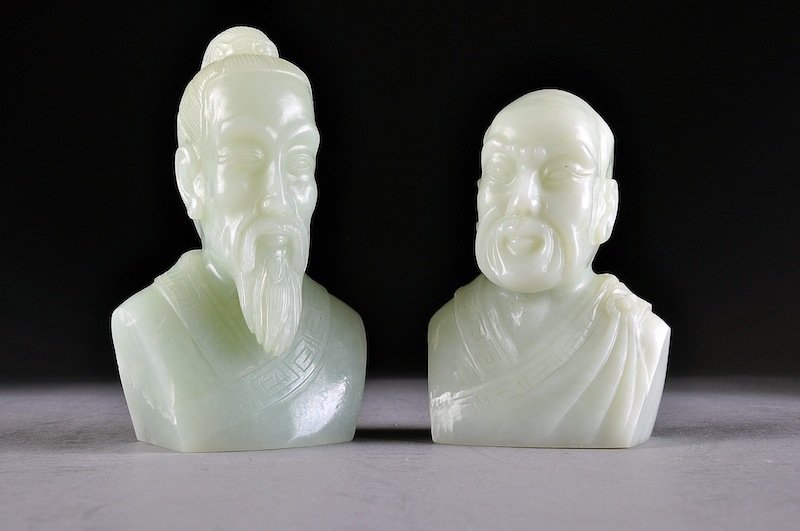 TWO CHINESE CARVED CELADON JADE BUSTS OF SAGES, 20T: TWO CHINESE CARVED CELADON JADE BUSTS OF SAGES, 20TH CENTURY, each truncated at the shoulders and comprising a bearded elder with upswept hair in a chignon above a serious expression, height: 5"; the 