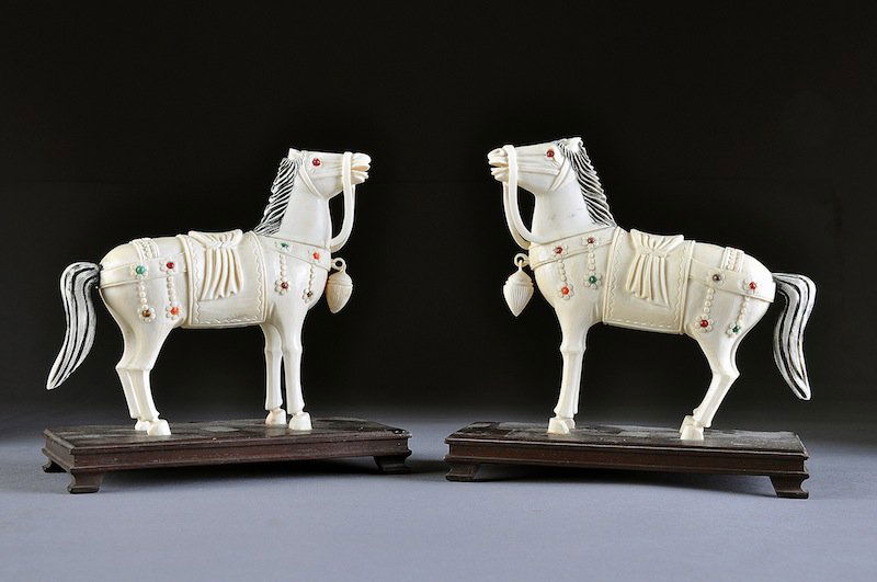 A PAIR OF VINTAGE CHINESE CARVED AND JEWELED IVORY: A PAIR OF VINTAGE CHINESE CARVED AND JEWELED IVORY HORSES, 20TH CENTURY, each in the archaistic style and modeled in an animated stance with black tinted waved manes above heavily lined detailed heads