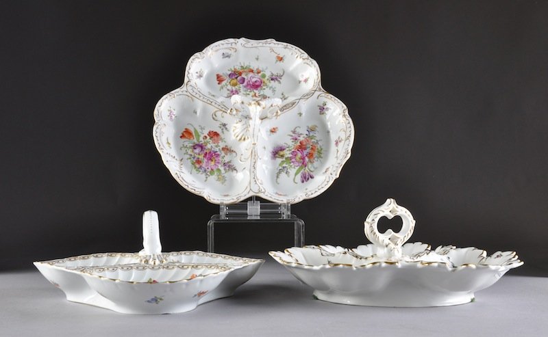 A GROUP OF THREE DRESDEN PARCEL GILT AND POLYCHROM: A GROUP OF THREE DRESDEN PARCEL GILT AND POLYCHROME PAINTED CONDIMENTS SERVING TRAYS, VARIOUS DECORATING COMPANIES, EARLY 20TH CENTURY, comprising a Carl Thieme three compartment tray with twist scall