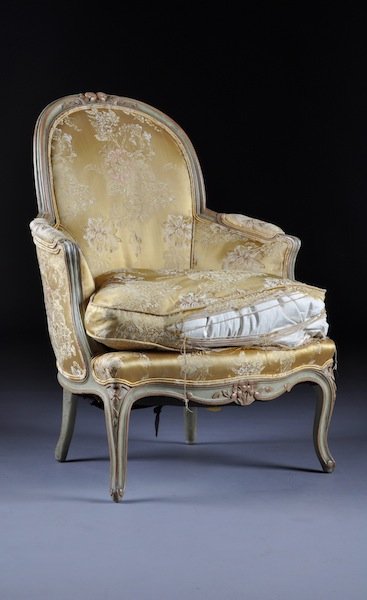 A LOUIS XV PAINTED AND CARVED WOOD BERGÈRE EN CABR: A LOUIS XV PAINTED AND CARVED WOOD BERGÈRE EN CABRIOLET, MID-18TH CENTURY, the arched padded back with floral pendant details continuing to padded arms on scrolled supports enclosing a drop in cushio