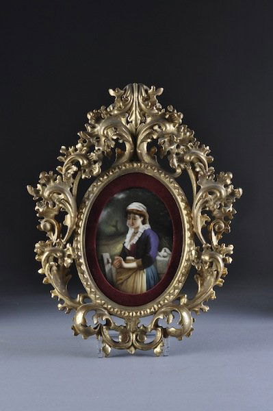A GERMAN PORCELAIN PLAQUE, "AN ENGAGED LADY," oval: A GERMAN PORCELAIN PLAQUE, "AN ENGAGED LADY," oval, within a carved gilt wood frame. Height of plaque: 9 1/2"