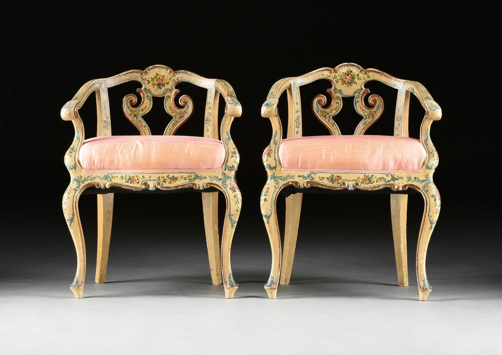 A PAIR OF VENETIAN ROCOCO REVIVAL BERGÈRE EN GONDOLE SALON ARMCHAIRS, ITALIAN, 19TH CENTURY: A PAIR OF VENETIAN ROCOCO REVIVAL BERGÈRE EN GONDOLE SALON ARMCHAIRS, ITALIAN, 19TH CENTURY, the broken arched crest over a reserve painted with floral bouquet over a vasiform form within two pin