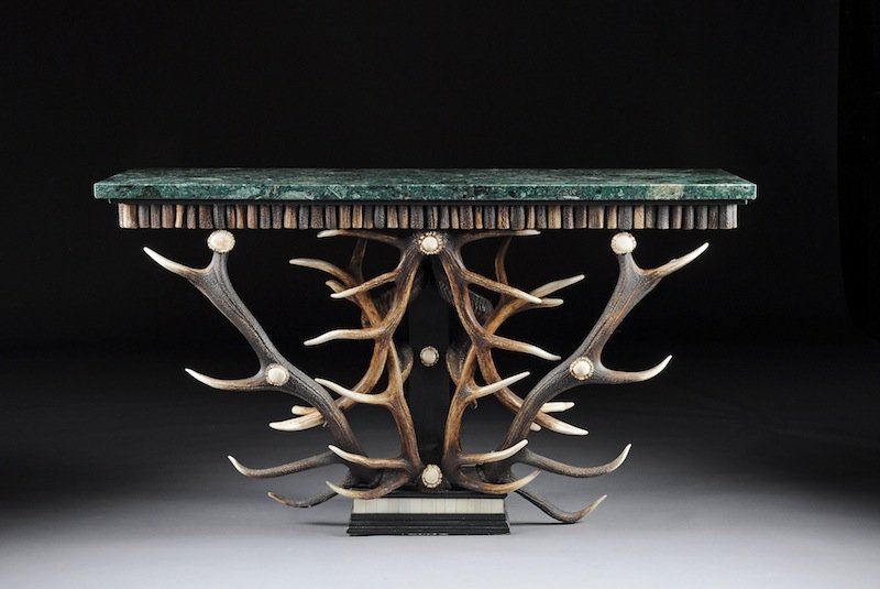 A LODGE STYLE DEER ANTLER MIRROR AND MARBLE TOP CON: A LODGE STYLE DEER ANTLER MIRROR AND MARBLE TOP CONSOLE TABLE, MODERN, the rectangular beveled mirror within a conforming black painted frame enclosing interlocking stag's antlers, height 57", width 5