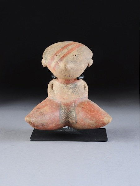 A PRE-COLUMBIAN CHINESCO NAYARIT FIGURE, the earth: A PRE-COLUMBIAN CHINESCO NAYARIT FIGURE, the earthenware figure modeled with subtle, minimalist featured seated with legs spread with remnants of black and red pigment with orange lines across the fac