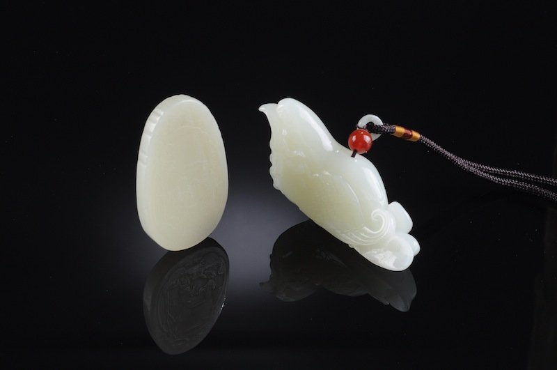 TWO CHINESE CARVED PALE CELADON JADE PENDANTS, POS: TWO CHINESE CARVED PALE CELADON JADE PENDANTS, POSSIBLY 19TH AND 20TH CENTURY, the oval form pendant having the face centering a scene of a bearded sage and frolicking youth amidst a waterside bamboo