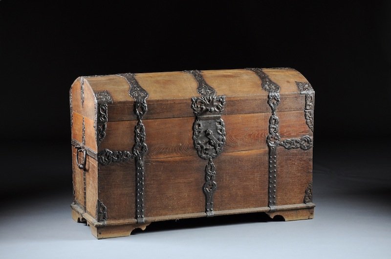 A CONTINENTAL WROUGHT-IRON MOUNTED OAK COFFER, POS: A CONTINENTAL WROUGHT-IRON MOUNTED OAK COFFER, POSSIBLY DUTCH, 17TH CENTURY, the arched hinged lid centering reticulated straps of scrolling and incised line decoration continuing down sides enclosing