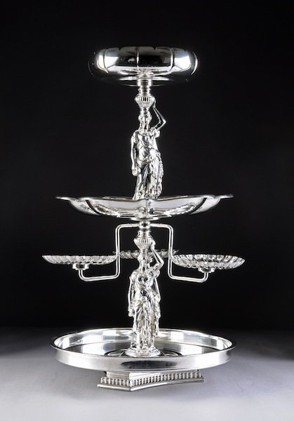 AN AMERICAN NEOCLASSICAL STYLE FOUR TIERED SILVER: AN AMERICAN NEOCLASSICAL STYLE FOUR TIERED SILVER PLATED CENTERPIECE, BY LOEVSKY & LOEVSKY WHITE METAL CASTINGS, NEW JERSEY, 20TH CENTURY, the central stem composed of classical maidens in long drapin