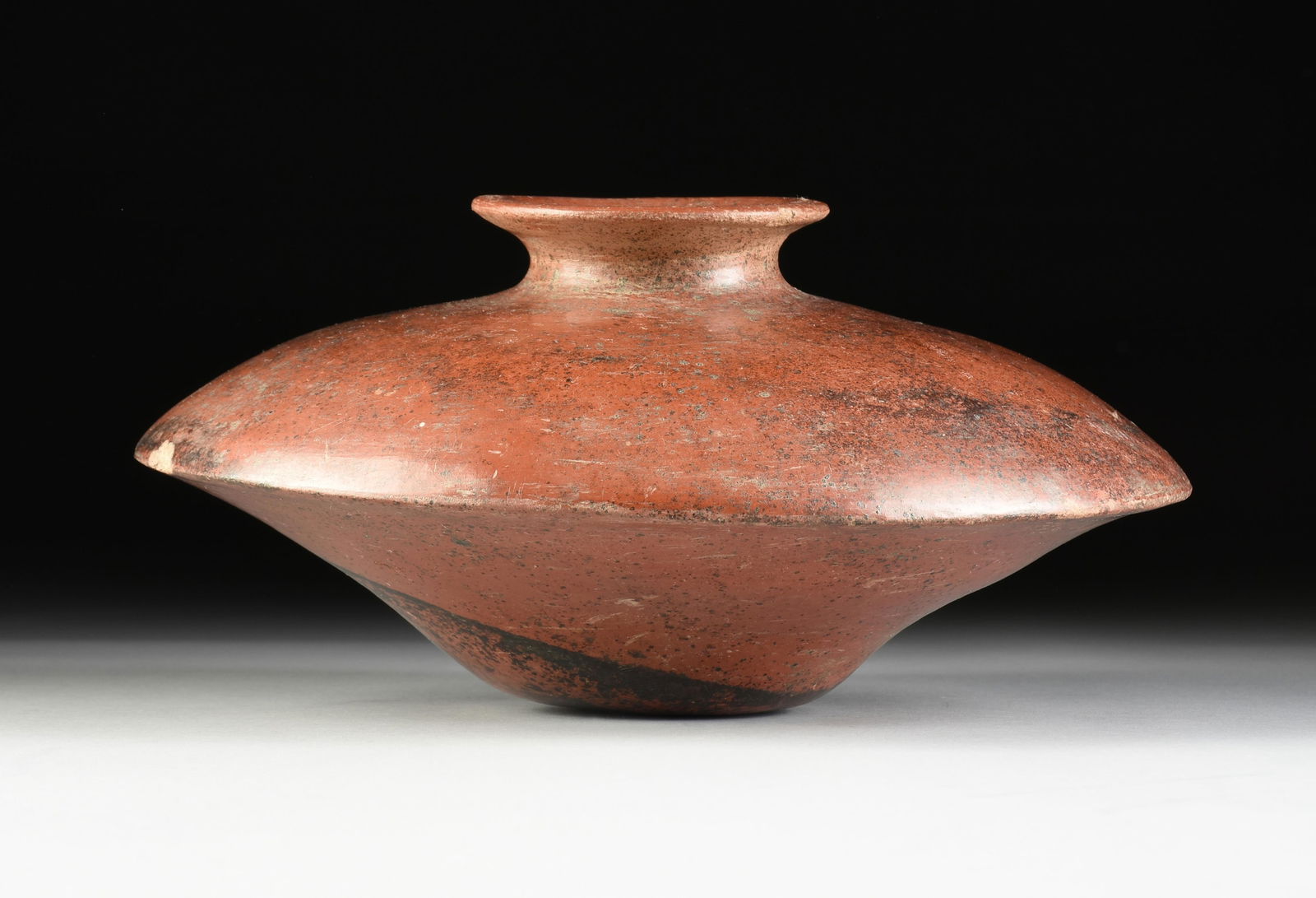 A PRE-COLUMBIAN REDWARE SAUCER FORM VESSEL, POSSIBLY COLIMA, MEXICO, 2ND CENTURY BC-AD 3RD CENTURY: A PRE-COLUMBIAN REDWARE SAUCER FORM VESSEL, POSSIBLY COLIMA, MEXICO, 2ND CENTURY BC-AD 3RD CENTURY, the large vessel with everted mouth and pinched neck over a compressed "mushroom" form body over a t