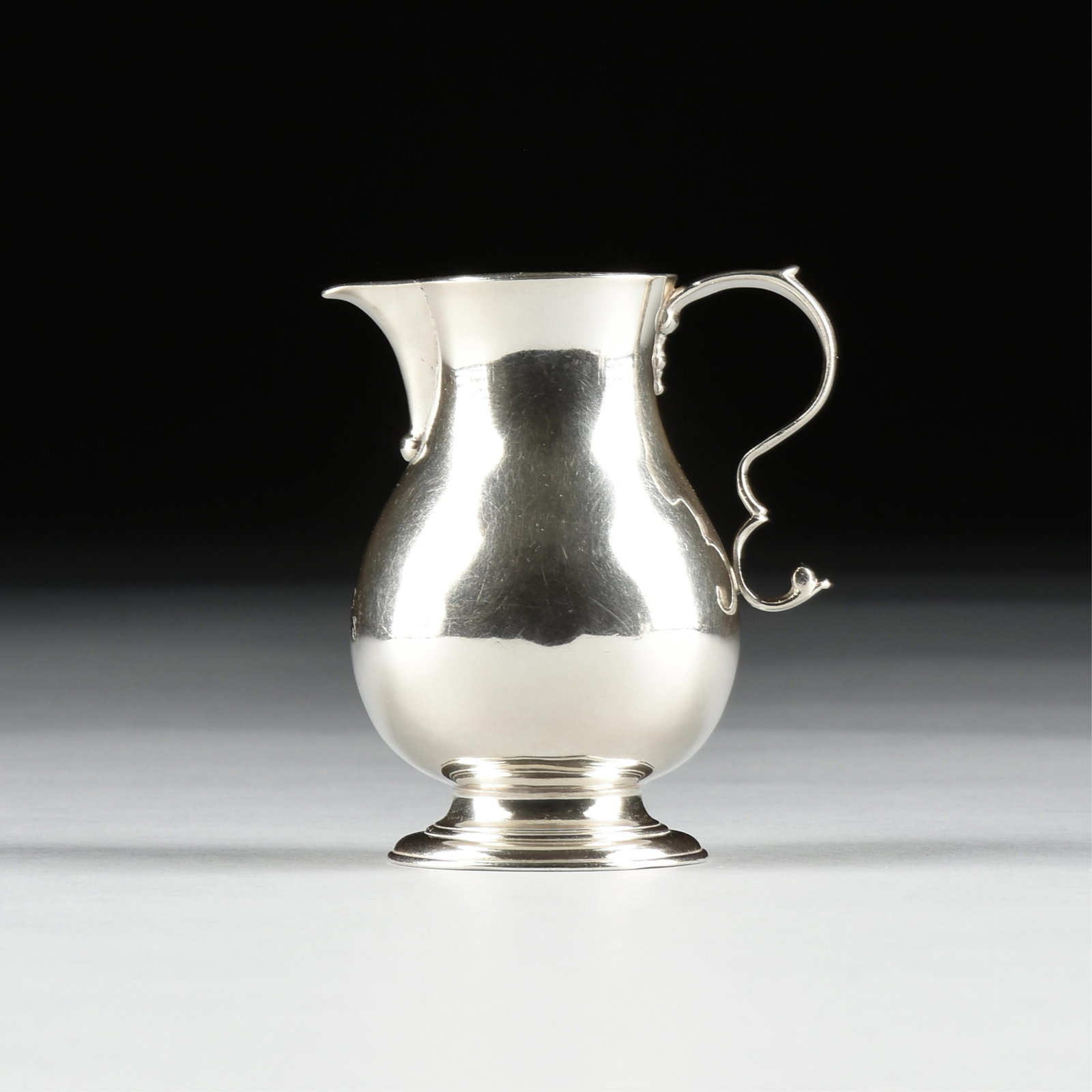 A GEORGE II STERLING SILVER CREAM PITCHER, ATTRIBUTED TO WILLIAM GARRARD, LONDON, CIRCA 1739-1740: A GEORGE II STERLING SILVER CREAM PITCHER, ATTRIBUTED TO WILLIAM GARRARD, LONDON, CIRCA 1739-1740, fully hallmarked on foot, marked "W.G." with monogram on vessel; height: 3 3/4", total approximate we
