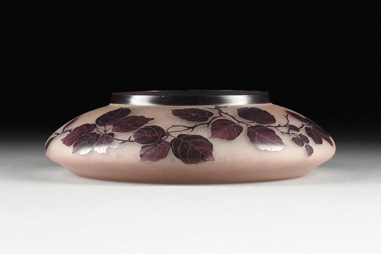 A VERRERIES D'ART LORRAIN CAMEO AND ENAMELED FROSTED GLASS "BERRIED LEAFY BRANCHES" CENTERPIECE: A VERRERIES D'ART LORRAIN CAMEO AND ENAMELED FROSTED GLASS "BERRIED LEAFY BRANCHES" CENTERPIECE VASE, SIGNED, EARLY 20TH CENTURY, of compressed circular form with sloping shoulders centering deep purp