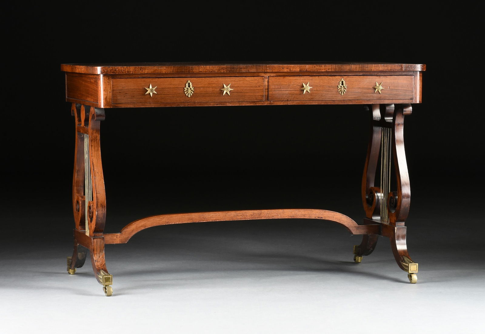 A REGENCY ROSEWOOD LIBRARY TABLE, ENGLISH, CIRCA 1810,: A REGENCY ROSEWOOD LIBRARY TABLE, ENGLISH, CIRCA 1810, a rosewood writing table with two apron drawers, lyre form supports, ormolu mounts, and with brass casters in the style of John McLean (English 1