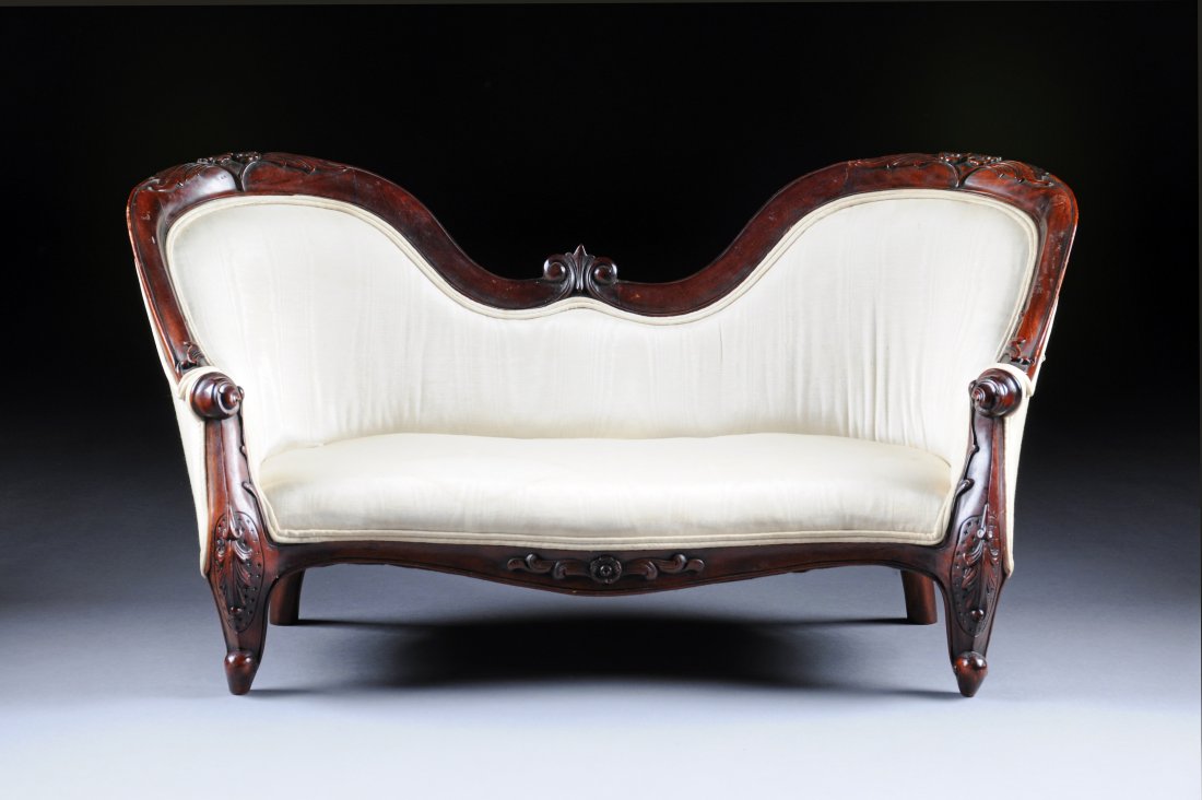 A VICTORIAN STYLE CARVED MAHOGANY CHILD'S SETTEE, : A VICTORIAN STYLE CARVED MAHOGANY CHILD'S SETTEE, the double arched crest rail centering paired floral sprays above an ivory silk moiré upholstered backrest and conforming seat, raised on cabriole le