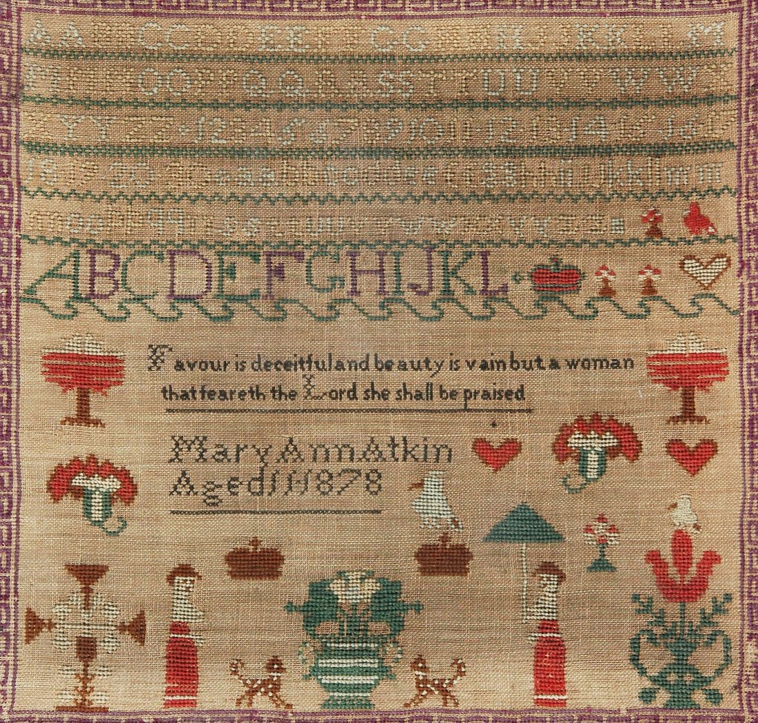 A FRAMED EMBROIDERY SAMPLER IN WOOL ON COARSE LIN: A FRAMED EMBROIDERY SAMPLER IN WOOL ON COARSE LINEN CANVAS, SIGNED "MARY ANN ATKIN, AGED 11, 1878", internally framed with an embroidered purple greek key pattern, the upper register with six lines of