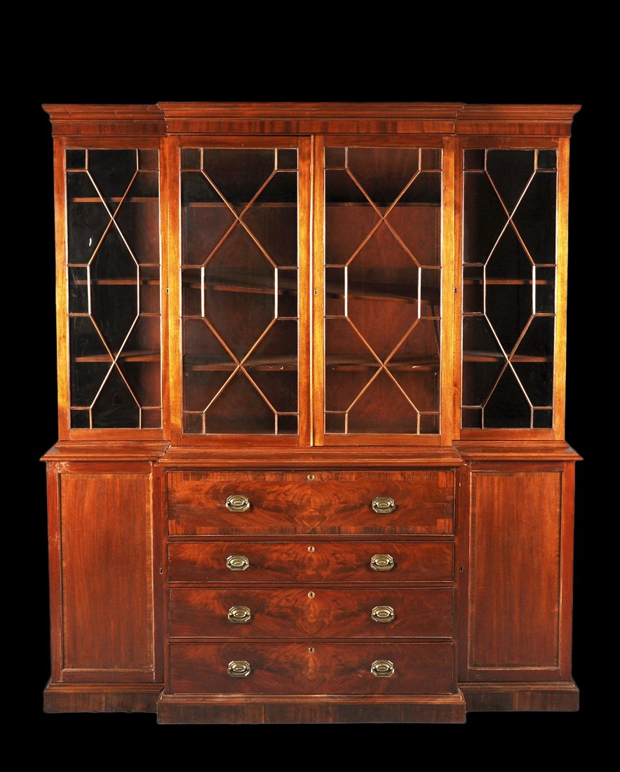 A GEORGE III STYLE MAHOGANY BREAKFRONT SECRETARY: A GEORGE III STYLE MAHOGANY BREAKFRONT SECRETARY BOOKCASE BY KITTINGER, MODERN, the molded rectangular breakfront cornice above paired glazed doors with stylized gothic mullions flanked by similarly g