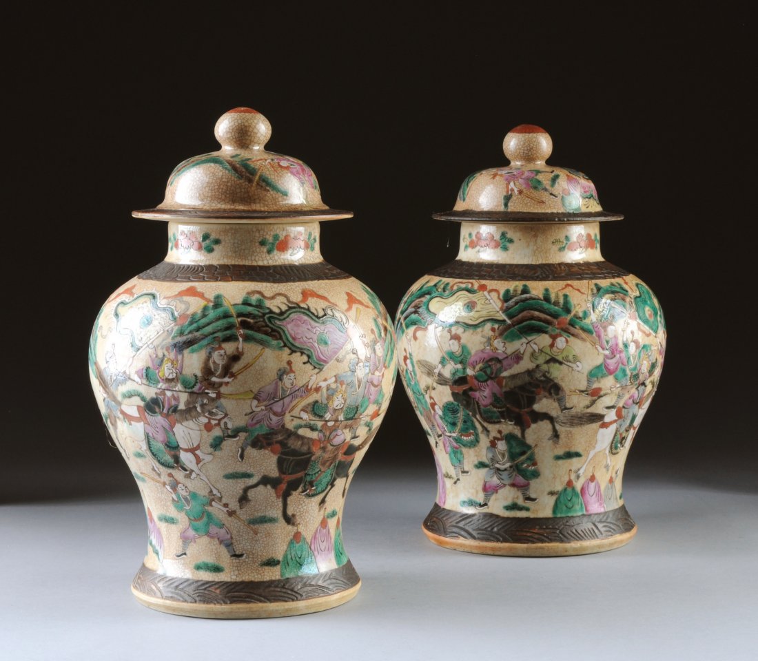 A PAIR OF CHINESE FAMILLE ROSE COVERED GINGER JAR: A PAIR OF CHINESE FAMILLE ROSE COVERED GINGER JARS, POSSIBLY REPUBLIC PERIOD, 20TH CENTURY, each of shaped baluster form with sides centering a continuous battle scene depicting opposing figures on ho