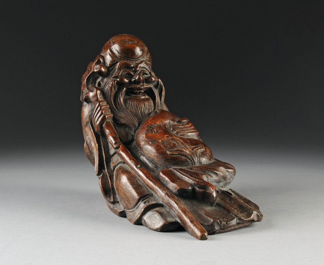 A VINTAGE CHINESE CARVED BAMBOO SCULPTURE OF LOUHAN, FI: A VINTAGE CHINESE CARVED BAMBOO SCULPTURE OF LOUHAN, FIRST-HALF 20TH CENTURY, depicted seated wearing long robes and holding a large peach in his lap and a staff in his right hand beneath a bearded la